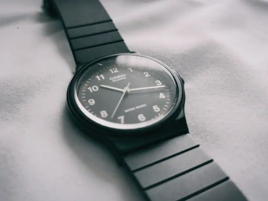 Close-up of a classic Casio quartz watch with black strap on a fabric surface.